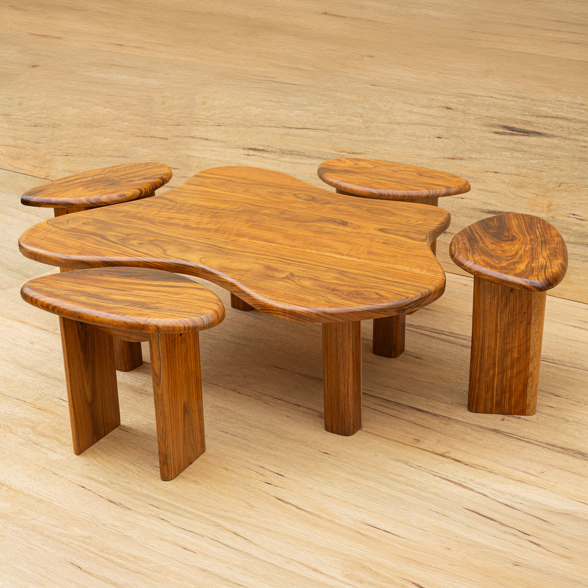 Ensemble Teri, table basse et quatre tabourets, posé sur un sol en bois